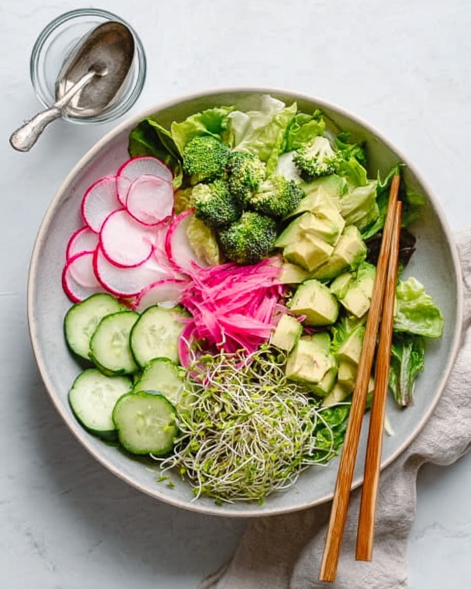 A large white bowl filled with fresh salad ingredients arranged in separate sections: bright green lettuce leaves spread around the edges, thin slices of light pink radish layered neatly on one side, cucumber rounds stacked in a small pile, chunks of creamy avocado placed beside the cucumbers, a pile of bright green broccoli florets near the top, and some sprouts with their delicate stems resting at the front. There is a small mound of thinly sliced pink pickled onions in the center. Two wooden chopsticks rest on the edge of the bowl. In the background, a small glass cup with a metal spoon is visible on a white marbled surface. photo taken with an iphone --ar 4:5 --v 7