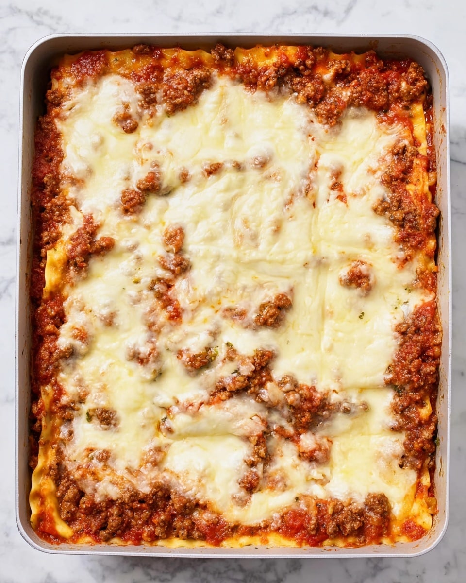 A square pan filled with four layers of lasagna. The bottom layer is a mix of browned ground meat and reddish tomato sauce, visible along the edges. Above this is a thin orange layer of pasta sheets, partly covered by more meat and sauce, showing a rich red and brown texture. The top two layers are thick, melted white cheese with a few golden spots and slight browning, spread unevenly with some gaps revealing the tomato sauce and meat underneath. The pan sits on a white marbled surface. Photo taken with an iphone --ar 4:5 --v 7