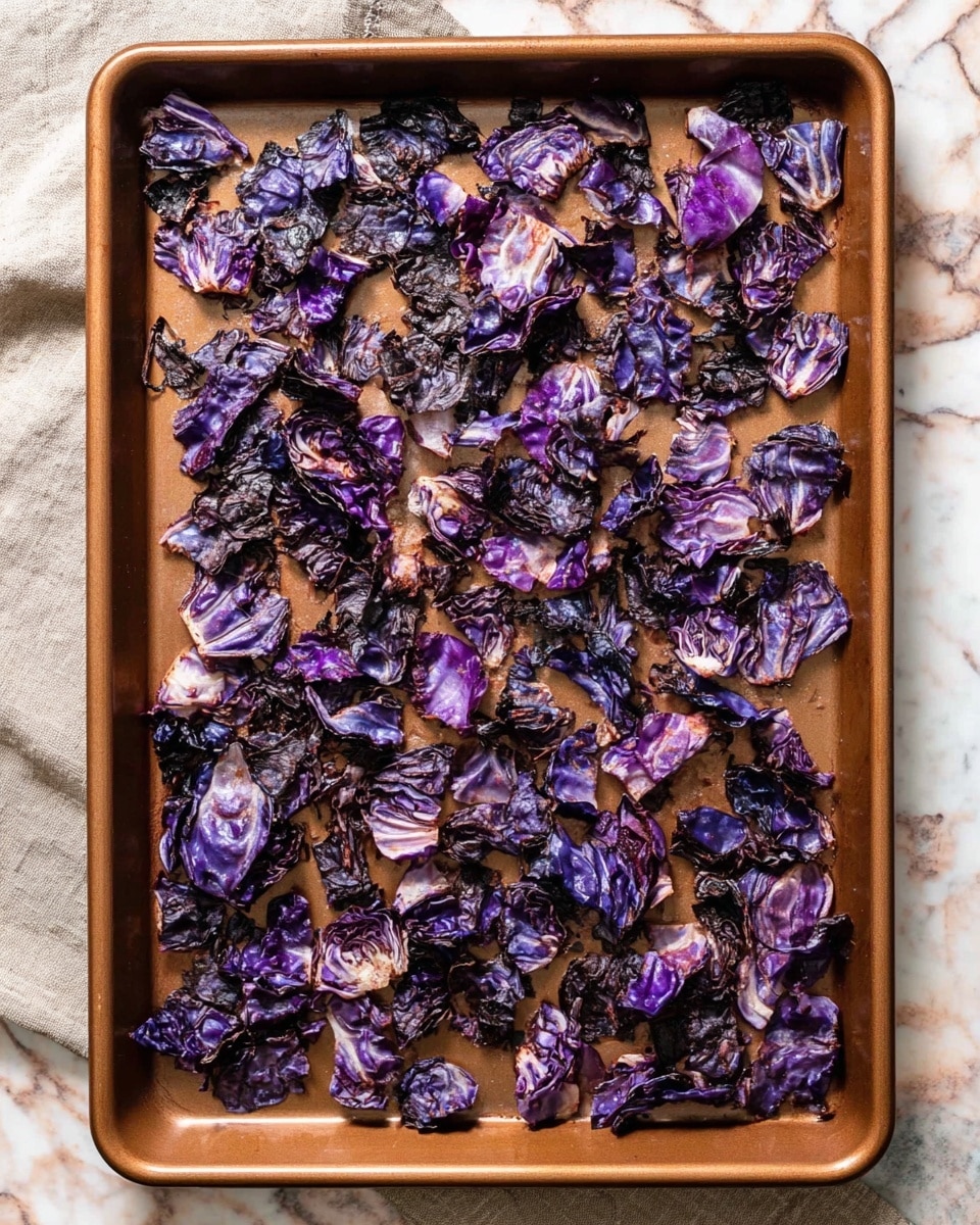 A baking tray filled with one layer of roasted purple cabbage pieces that are unevenly cut, some with slightly curled edges. The cabbage has a mix of deep purple and black charred parts, showing a crispy texture from roasting. The tray is a warm brown color and rests on a surface with a white marbled texture. Photo taken with an iphone --ar 4:5 --v 7
